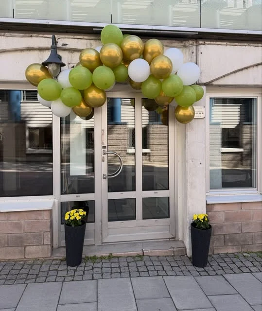 Caféets entré på Skomakargatan, dekorerad med gröna och guldfärgade ballonger.